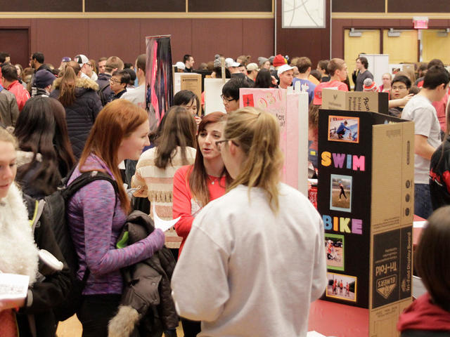 View of students interacting at an involvement & resource fair with a variety of poster boards.